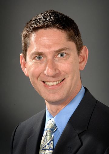 Bradley Sherman, MD, wearing a blue shirt and multi-colored tie